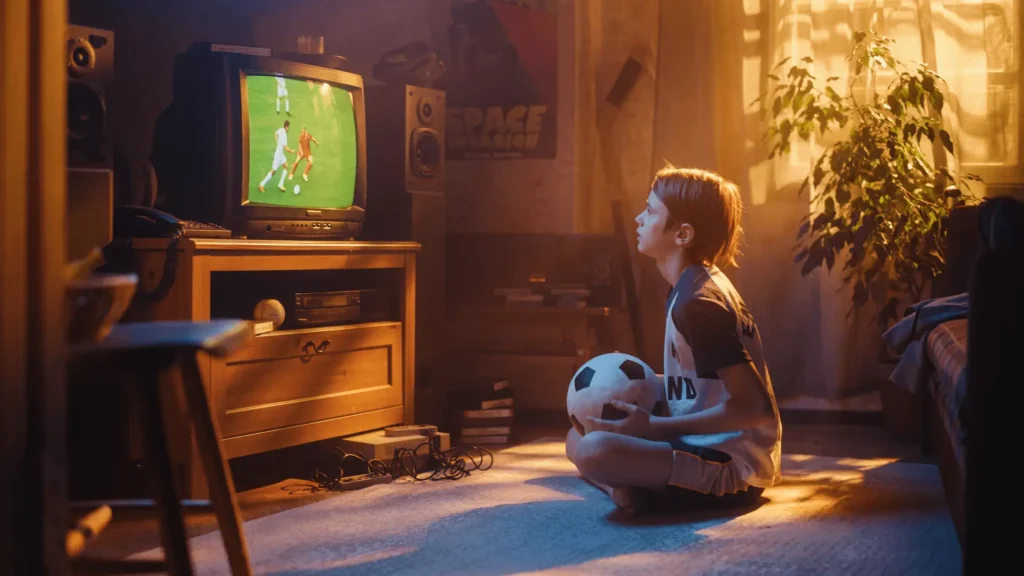 Kleiner Junde sitz vor dem Fernseher und schaut ein Fussballspiel