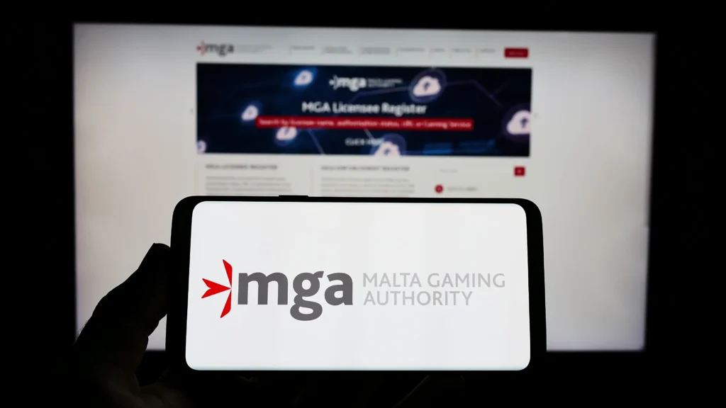 MGA Malta Gaming Authority - Smartphone vor einem Bildschirm - Beides zeigt das MGA Logo