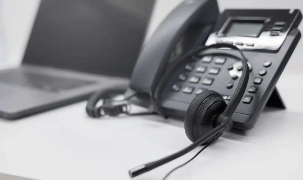 Telefon mit Headset deneben - Symbol für den Kunden Support